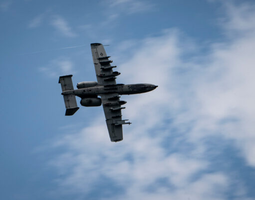 British controllers direct A-10 strikes Underside view of a gray four-engine propeller aircraft (C-130) flying overhead against a blue sky.