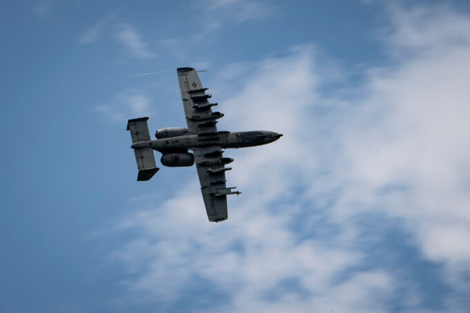 British controllers direct A-10 strikes Underside view of a gray four-engine propeller aircraft (C-130) flying overhead against a blue sky.