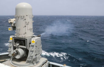 British warship opens fire in the Arabian Sea Naval gun turret on a gray battleship or naval vessel, facing the open ocean with waves in the background