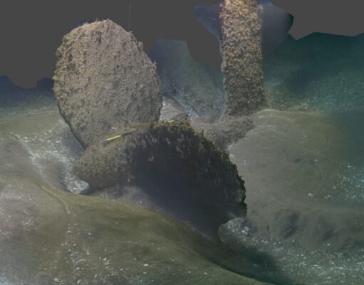 Warship cut in two found off the Isle of Wight Underwater rocky seabed with two tall, algae-covered pillars and a curved trench in sandy, dim water.
