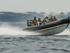Korean special forces train with Royal Marines in UK first Six soldiers in camouflage gear on a high-speed inflatable military boat skimming over the water with a misty shoreline in the background.