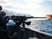 British warship opens fire near Falklands to deter Argentina Sailors on a naval deck firing a large mounted gun, muzzle flash over the ocean with a cloudy sky behind.