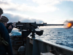 British warship opens fire near Falklands to deter Argentina Sailors on a naval deck firing a large mounted gun, muzzle flash over the ocean with a cloudy sky behind.