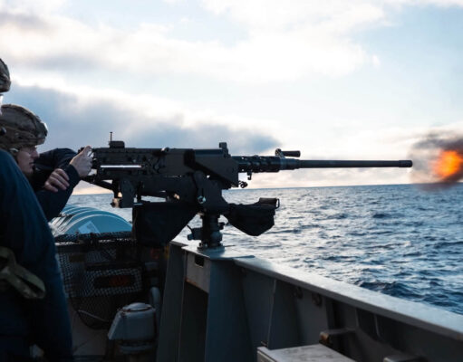 British warship opens fire near Falklands to deter Argentina Sailors on a naval deck firing a large mounted gun, muzzle flash over the ocean with a cloudy sky behind.