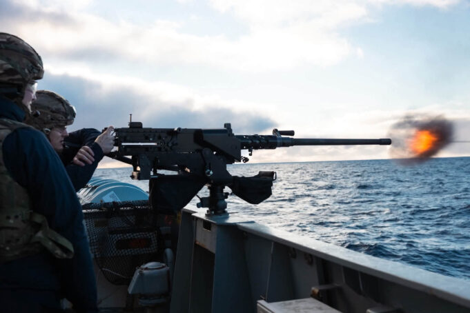 British warship opens fire near Falklands to deter Argentina Sailors on a naval deck firing a large mounted gun, muzzle flash over the ocean with a cloudy sky behind.
