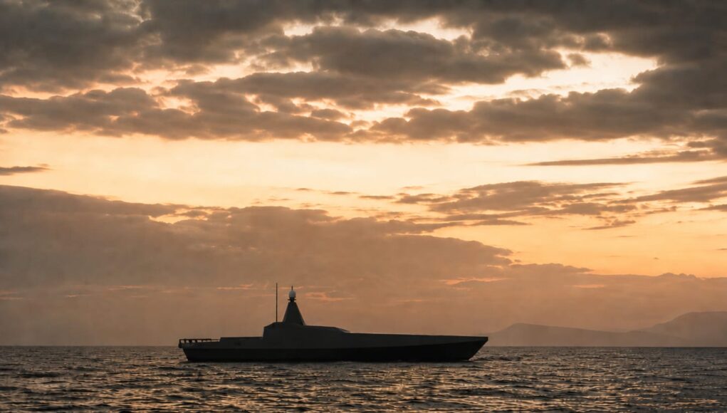IMG-20260806-WA0000 Silhouette of a modern motor yacht on the sea at sunset with an orange sky and distant horizon.