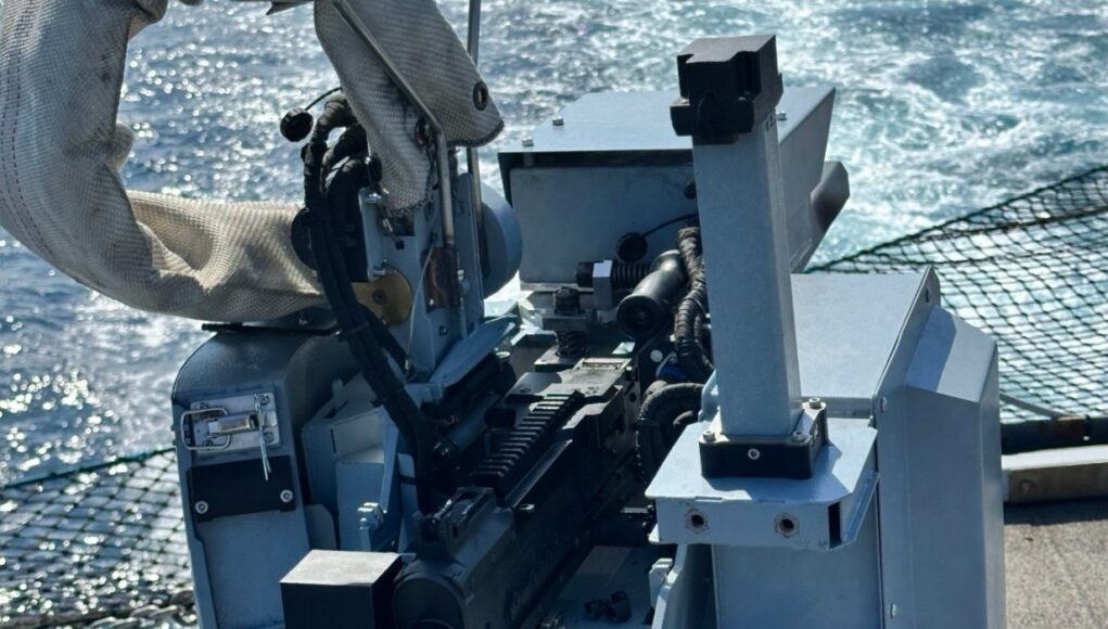 Predator Close-up of a ship-mounted automatic weapon, with cables and sight, ocean in the background.