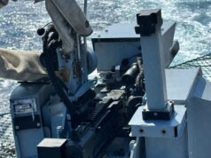 NATO warship destroys drones with new Ukrainian weapon Close-up of a ship-mounted automatic weapon, with cables and sight, ocean in the background.