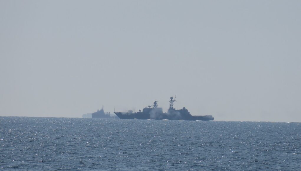 RFN Neustrashimy live firing monitored by HMS Tyne2 Two warships sailing on the open sea near the horizon, silhouetted against a pale sky.