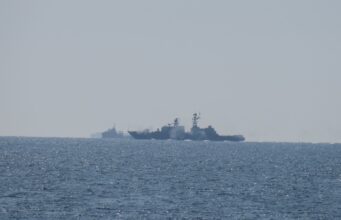 Russian warship opens fire near UK as British ship closes in Two warships sailing on the open sea near the horizon, silhouetted against a pale sky.