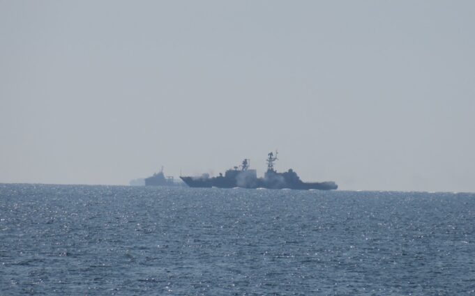 Russian warship opens fire near UK as British ship closes in Two warships sailing on the open sea near the horizon, silhouetted against a pale sky.