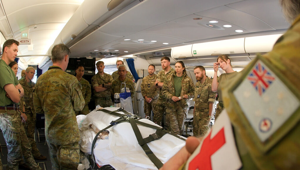 Sequence_0500_00_40_03Still003 Military medics gathered around a patient on a stretcher inside a military aircraft, preparing a medical evacuation.