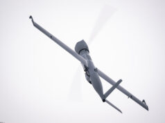 Airbus Flexrotor begins Baltic maritime surveillance work View of a gray helicopter seen from below with spinning rotor blades against a pale sky.