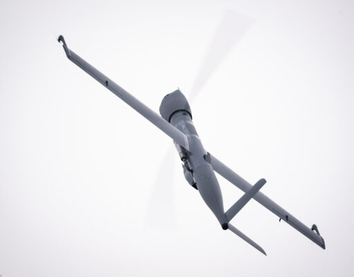 Airbus Flexrotor begins Baltic maritime surveillance work View of a gray helicopter seen from below with spinning rotor blades against a pale sky.