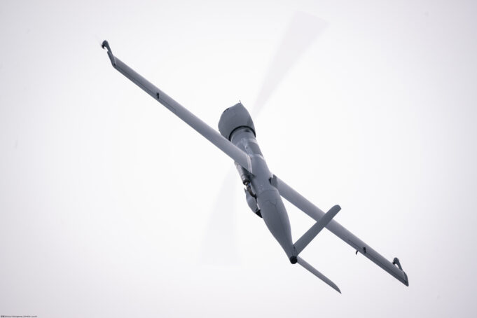 Airbus Flexrotor begins Baltic maritime surveillance work View of a gray helicopter seen from below with spinning rotor blades against a pale sky.