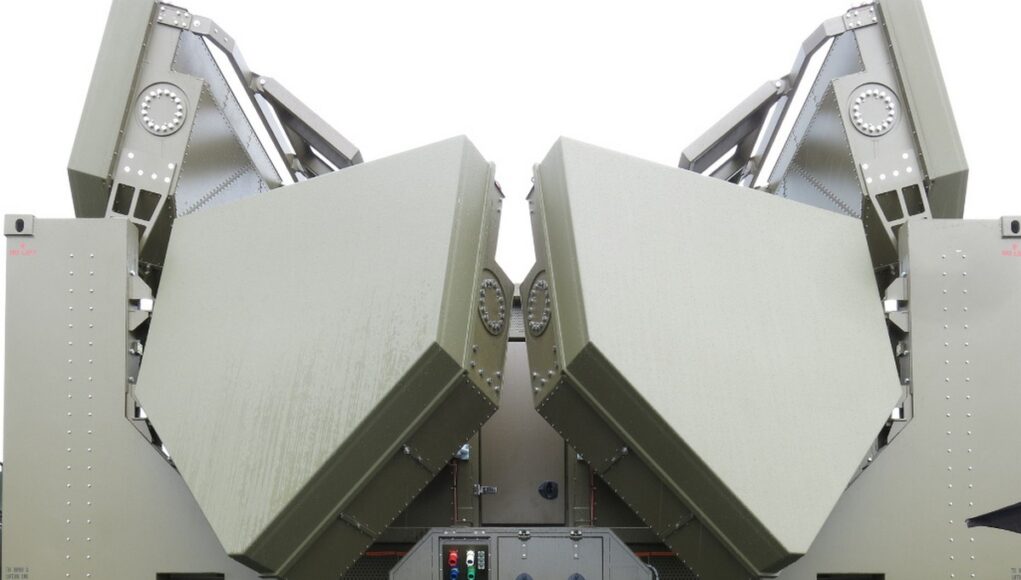 Two large olive-green panels folded into a symmetric V shape on a military vehicle, suggesting a radar or missile launcher mounted on a truck chassis.