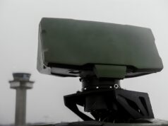 Radar network kept working after GPS timing was cut Close-up of a green military weapon mount on a vehicle with a blurred distant tower in the background