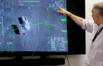 British firm Inzpire to train Ukrainian pilots in air tactics Person in a light shirt points at a large screen displaying a flight navigation/avionics interface with green markers and data.