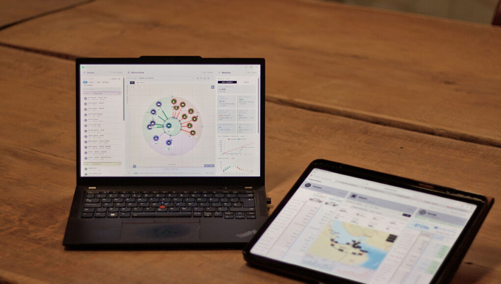 Laptop shows a circular data dashboard while a tablet displays a map dashboard on a wooden table.