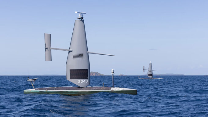 Autonomous sailing drone on a flat catamaran, a tall gray sail with the number 2040, sailing on open blue sea.