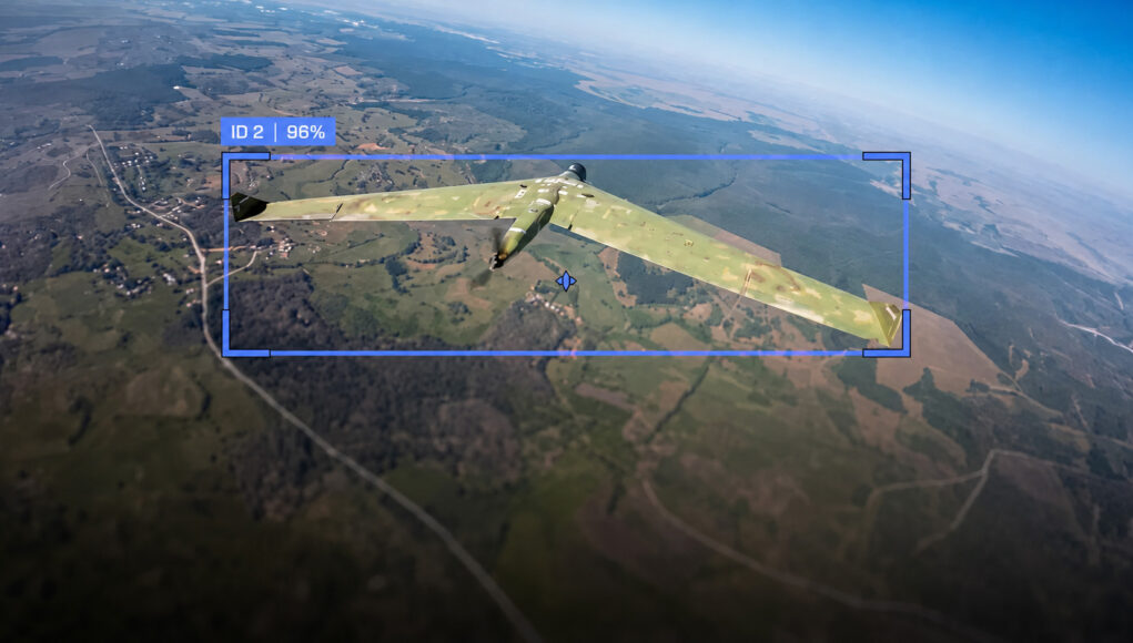 Camouflaged military aircraft in flight over farmland, with a blue HUD box showing ID 2 and 96%.