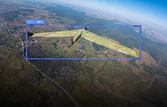 Camouflaged military aircraft in flight over farmland, with a blue HUD box showing ID 2 and 96%.