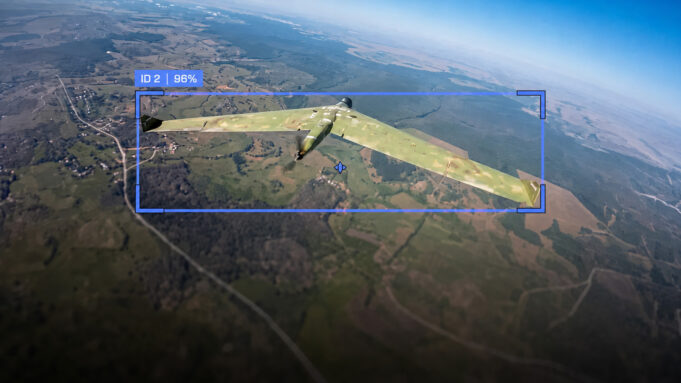 Camouflaged military aircraft in flight over farmland, with a blue HUD box showing ID 2 and 96%.